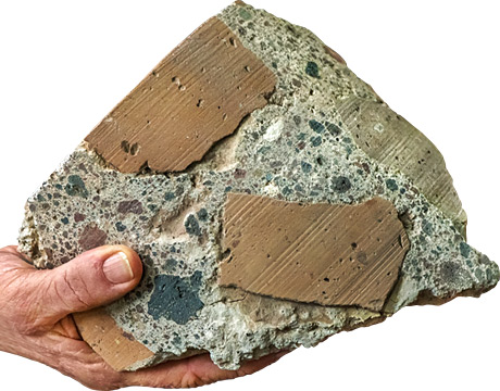 A hand holding a chunk of Roman concrete.